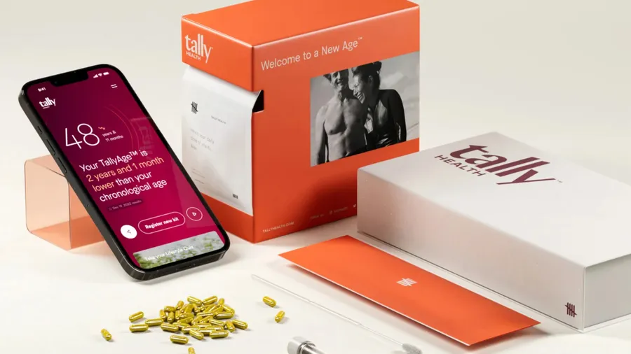 A cell phone with the Tally Health app displayed next to some boxes with supplements in the front