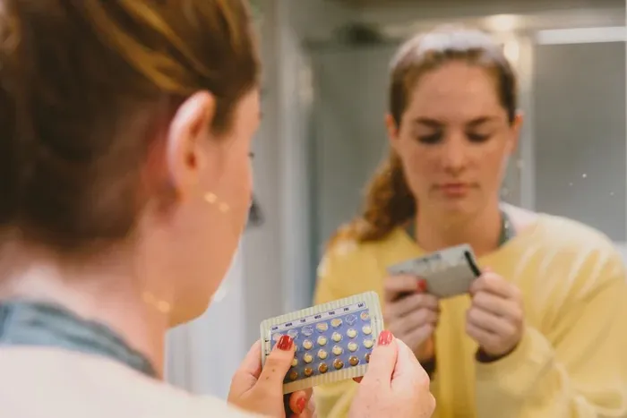 A woman looking at birth control pills.