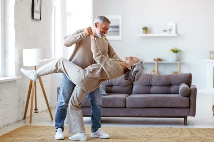 a man and woman are dancing and smiling in their living room.