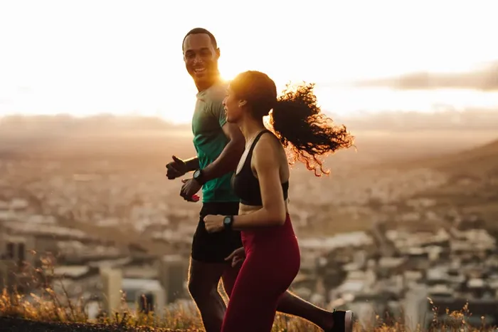 A man and a woman running on a hill.