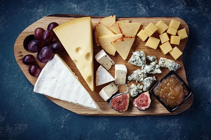 a wooden platter filled with different types of cheese